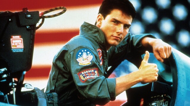 alt="Tom Cruise in Top Gun, where Val Kilmer starred as Iceman, giving a thumbs-up in a fighter jet."